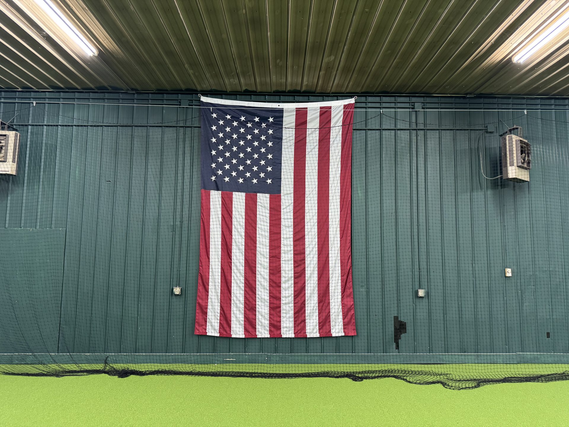 American flag hanging on the green metal wall inside Chenango SportsZone