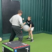 Coach working one-on-one with young athlete using medicine ball
