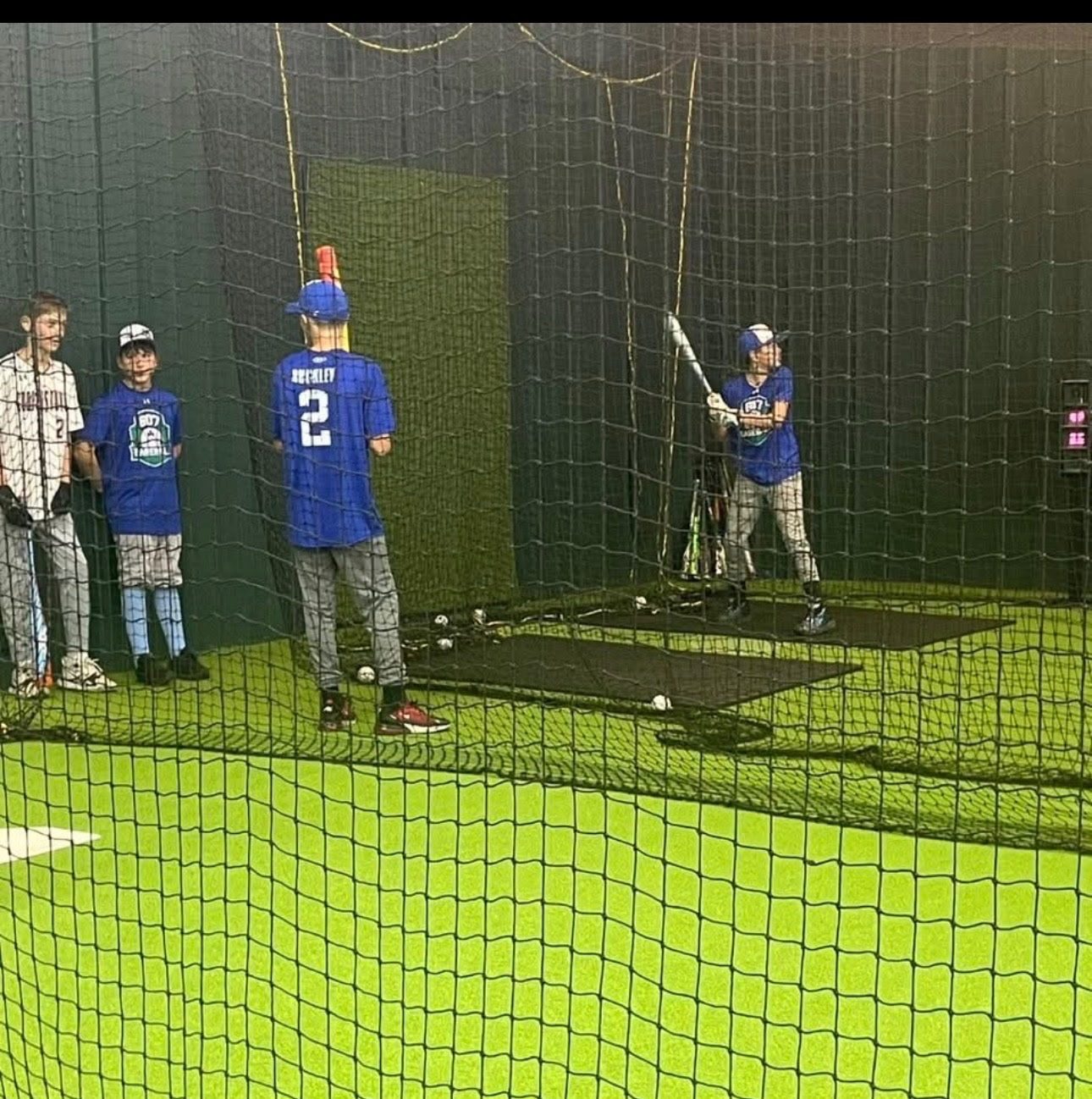 Coach working with young athletes in batting cages during a training session