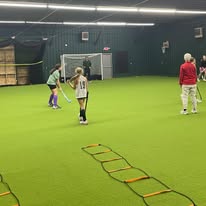 Youth field hockey players running agility ladder drills on the indoor turf